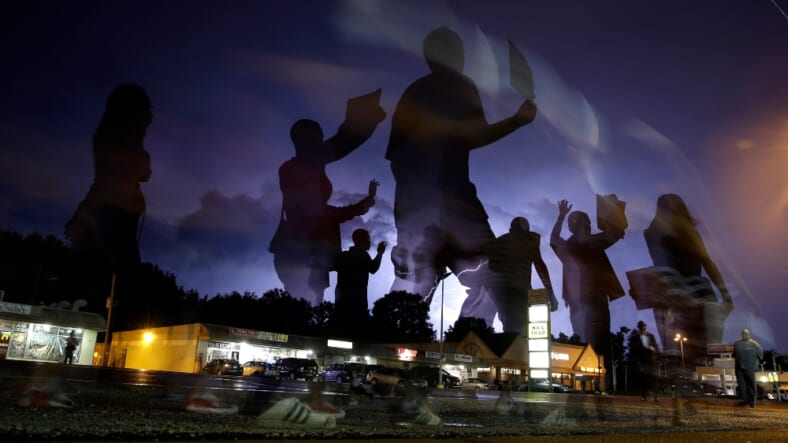 In this Aug. 20, 2014, file photo, protesters march in the street as lightning flashes in the distance in Ferguson, Mo. Michael Brown's death on Aug. 9, 2014, at the hands of a white Missouri police officer stands as a seismic moment of race relations in America. The fledgling Black Lives Matter movement found its voice, police departments fell under intense scrutiny, progressive prosecutors were elected and court policies revised. (AP Photo/Jeff Roberson, File)