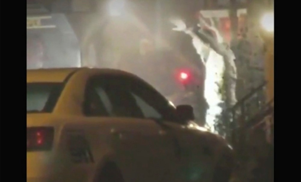 In this image from video taken by Bill Trenwith on Wednesday, Aug. 14, 2019, a man exits a building with hands up in Philadelphia, Pennsylvania. A gunman who opened fire on police Wednesday as they were serving a drug warrant in Philadelphia, wounding six officers and triggering a standoff that extended into the night, is in police custody, authorities said. (Bill Trenwith via AP) thegrio.com