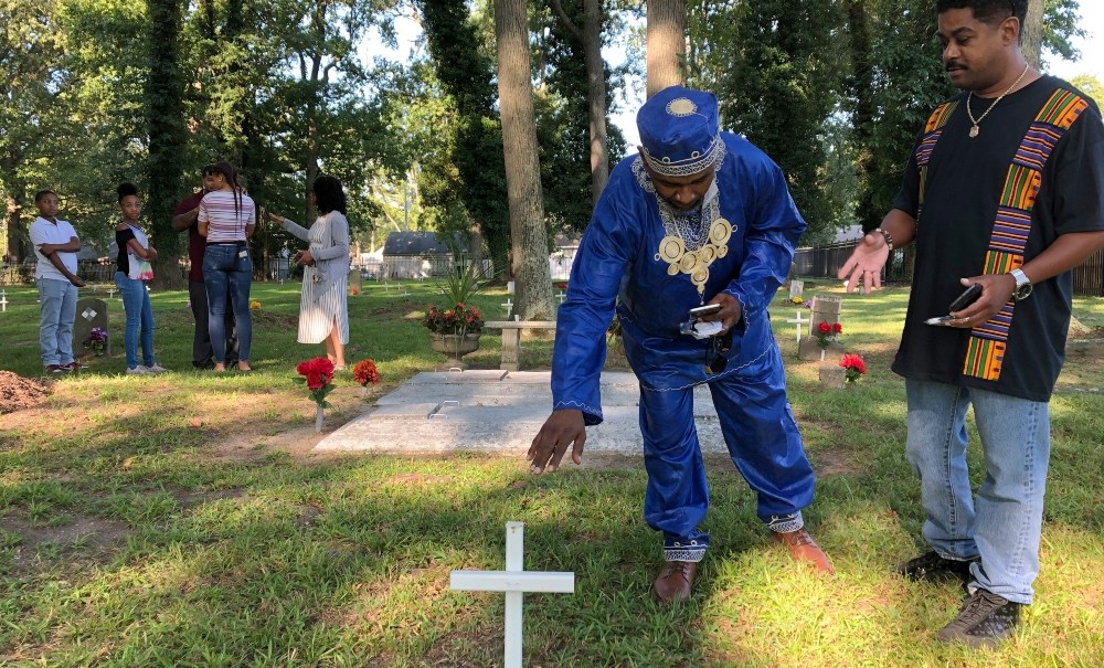 Andre Bradshaw, left, and Eric Jackson stand at an unmarked grave at the Tucker Family Cemetery in Hampton, Va. on Friday, Aug. 23, 2019. They are part of a larger family that traces its roots back to the first enslaved Africans to arrive in what is now Virginia in 1619. (AP Photo/Ben Finley) thegrio.com