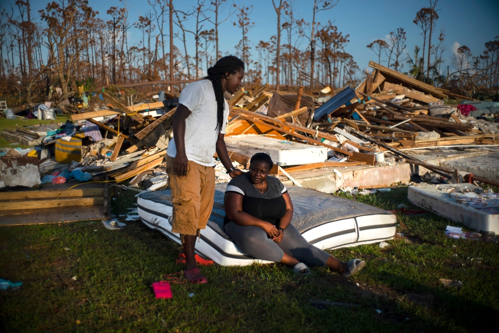 Synobia Reckley pauses on a wet mattress as her husband Dexter Edwards consoles her amid the remains of their home destroyed by Hurricane Dorian in Rocky Creek East End, Grand Bahama, Bahamas, Sunday, Sept. 8, 2019. The couple married two days after Hurricane Mathew hit in 2016 but did not do serious damage. (AP Photo/Ramon Espinosa) thegrio.com