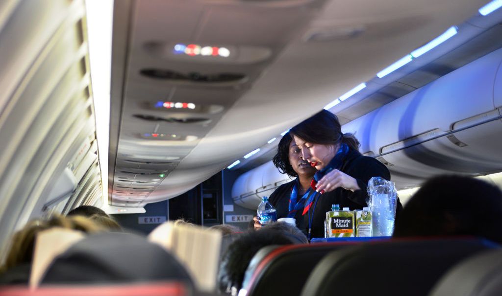 DALLAS, TEXAS - DECEMBER 12, 2018: Two American Airlines flight attendants serve drinks to passengers after departing Dallas/Fort Worth International Airport. (Photo by Robert Alexander/Getty Images) thegrio.com