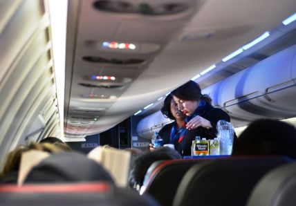 DALLAS, TEXAS - DECEMBER 12, 2018: Two American Airlines flight attendants serve drinks to passengers after departing Dallas/Fort Worth International Airport. (Photo by Robert Alexander/Getty Images) thegrio.com
