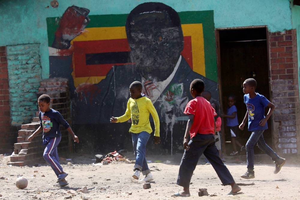 Children play soccer next to a defaced portrait of Former Zimbabwean President Robert Mugabe in Harare, Friday, Sept, 6 2019.Former Zimbabwean President Robert Mugabe has died, his successor president Emmerson Mnangagwa has confirmed. Mugabe was 95 and died at a Singapore Hospital.(AP Photo/Tsvangirayi Mukwazhi) thegrio.com