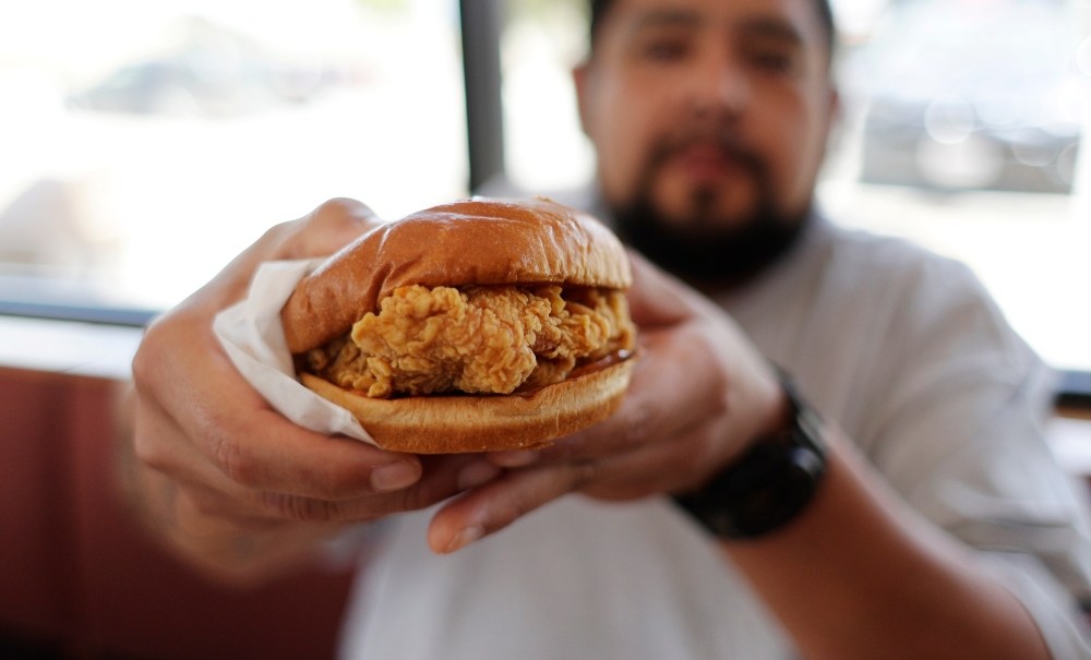 Randy Estrada holds up his chicken sandwiches at a Popeyes, Thursday, Aug. 22, 2019, in Kyle, Texas. A nation already polarized finds itself embroiled and divided once again, but this time, politics has nothing to do with it: The blame lays squarely on a fried piece of poultry.(AP Photo/Eric Gay) thegrio.com