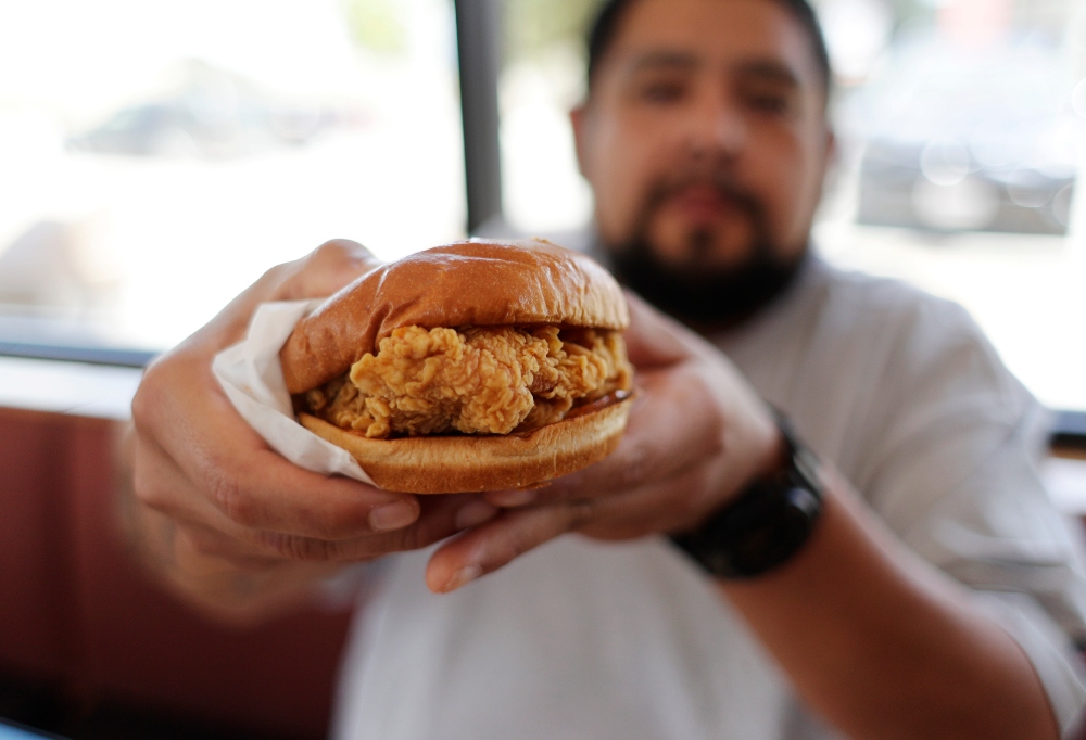 Randy Estrada holds up his chicken sandwiches at a Popeyes, Thursday, Aug. 22, 2019, in Kyle, Texas. A nation already polarized finds itself embroiled and divided once again, but this time, politics has nothing to do with it: The blame lays squarely on a fried piece of poultry.(AP Photo/Eric Gay) thegrio.com