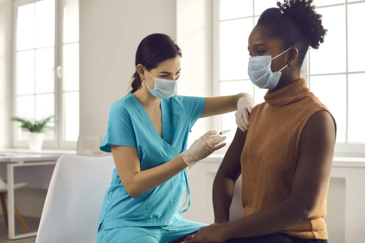 Black people health care system -- woman getting modern flu or Covid-19 vaccine at doctor's office