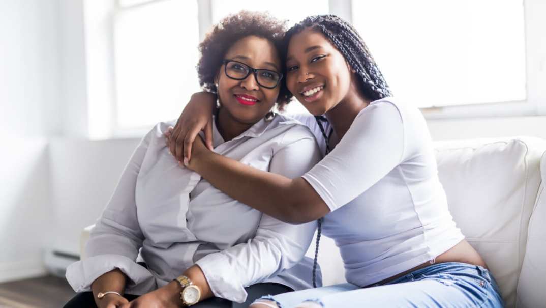 A affectionate mother and daughter sitting on a sofa