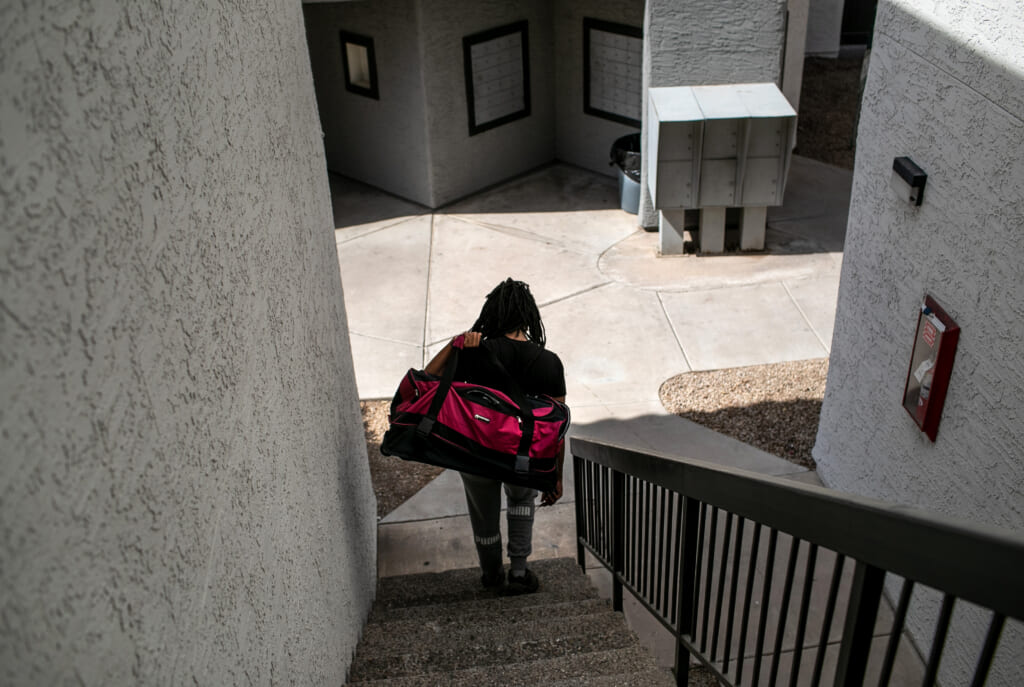 An apartment resident carries out a bag of clothing while being evicted