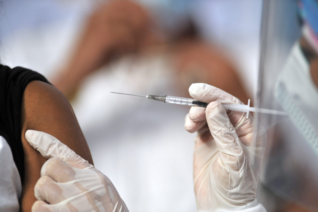 A health worker gives a man a shot of the Jenssen COVID-19 vaccine from the Johnson & Johnson - theGrio.com