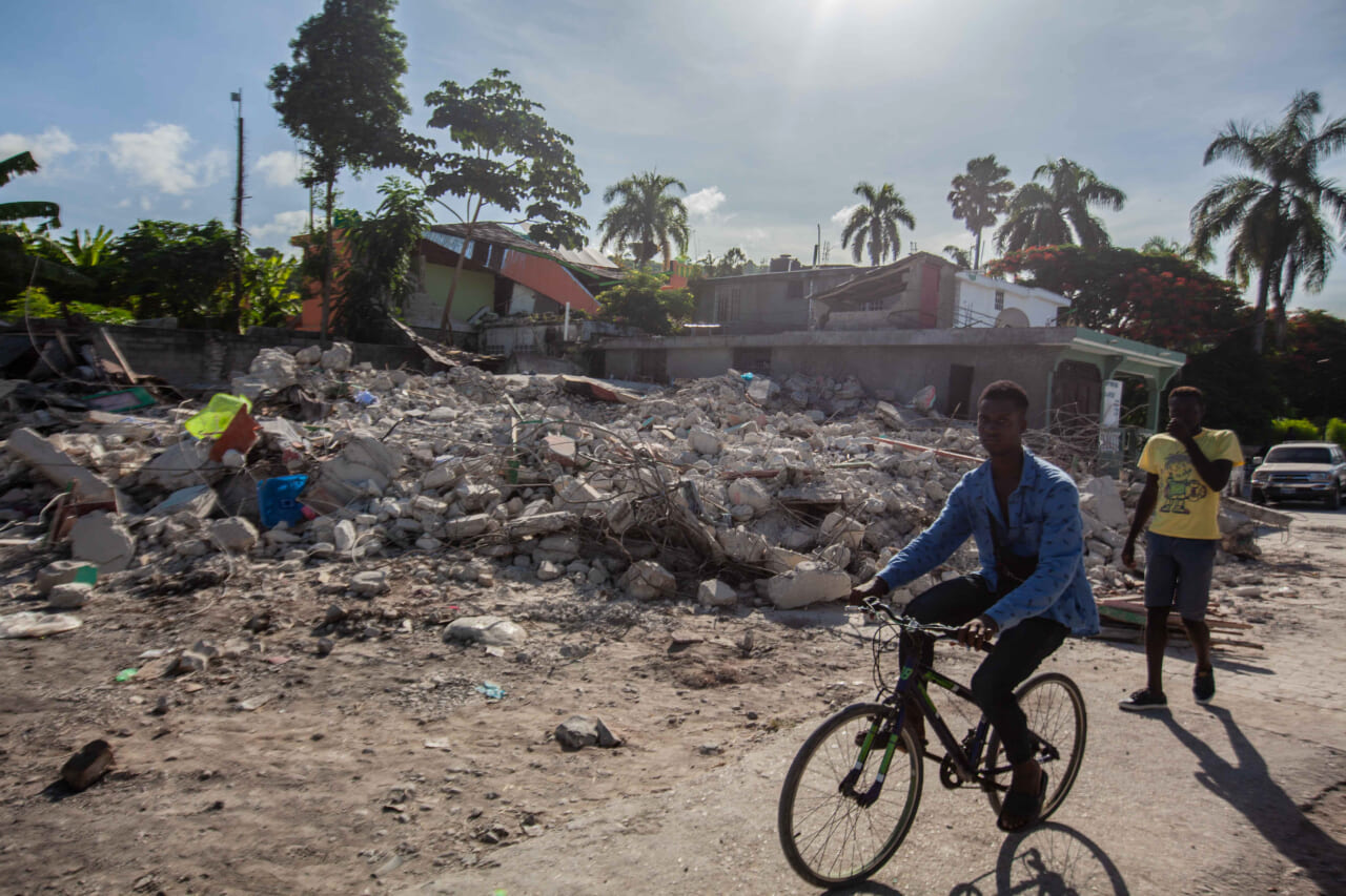 A man rides his bike by a collapsed building after a 7.2-magnitude earthquake struck Haiti