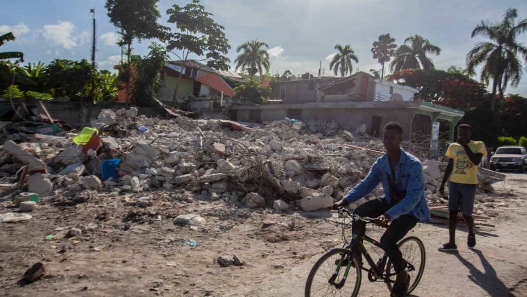 A man rides his bike by a collapsed building after a 7.2-magnitude earthquake struck Haiti