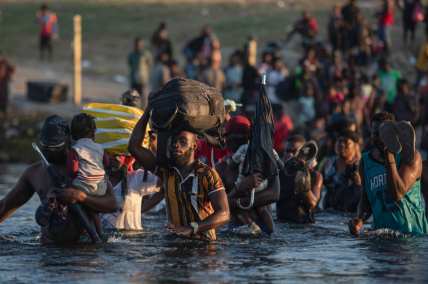 Migrants, many from Haiti, wade across the Rio Grande river from Del Rio, Texas, immigration