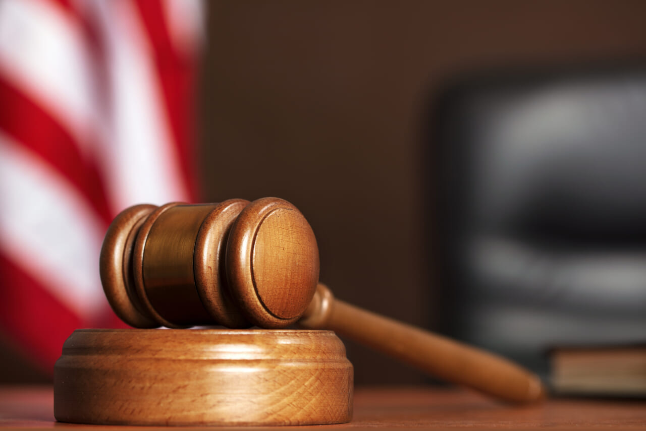 Judge Wooden gavel on the table of judge with american flag and black chair