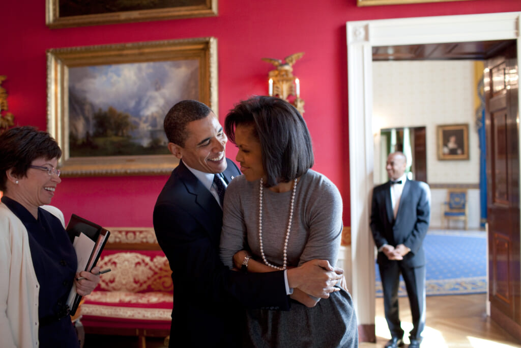President Barack Obama (R) hugs First Lady Michelle Obama in the Red Room while Senior Advisor Valerie Jarrett