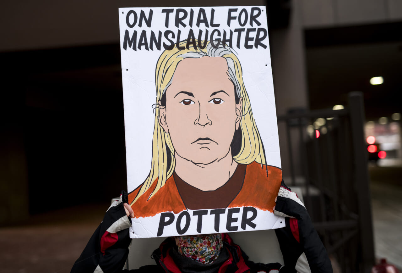 A demonstrator holds a sign with an image of Kim Potter