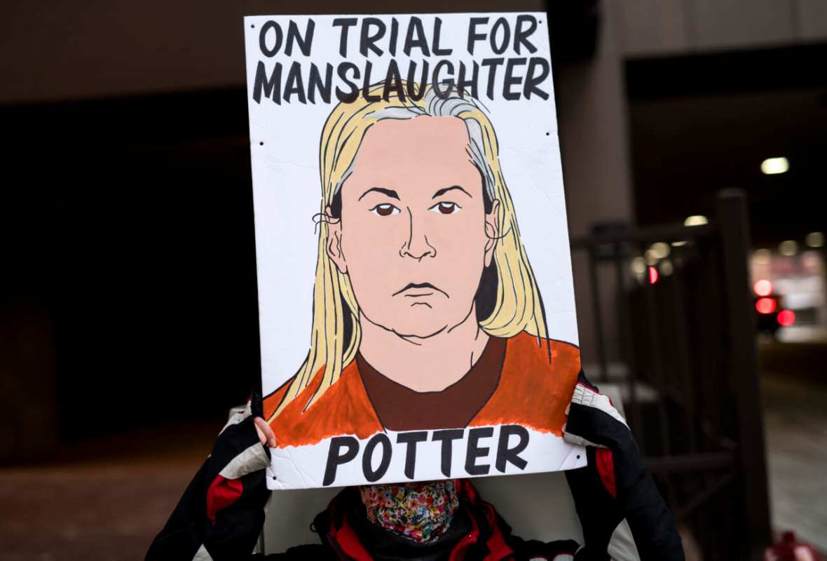 A demonstrator holds a sign with an image of Kim Potter