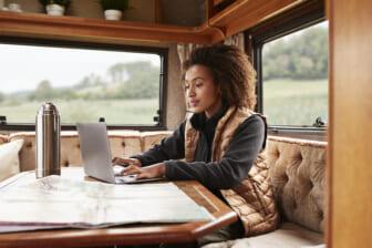 Woman using laptop in camper theGrio.com