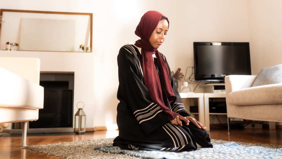 A Muslim woman kneels to pray