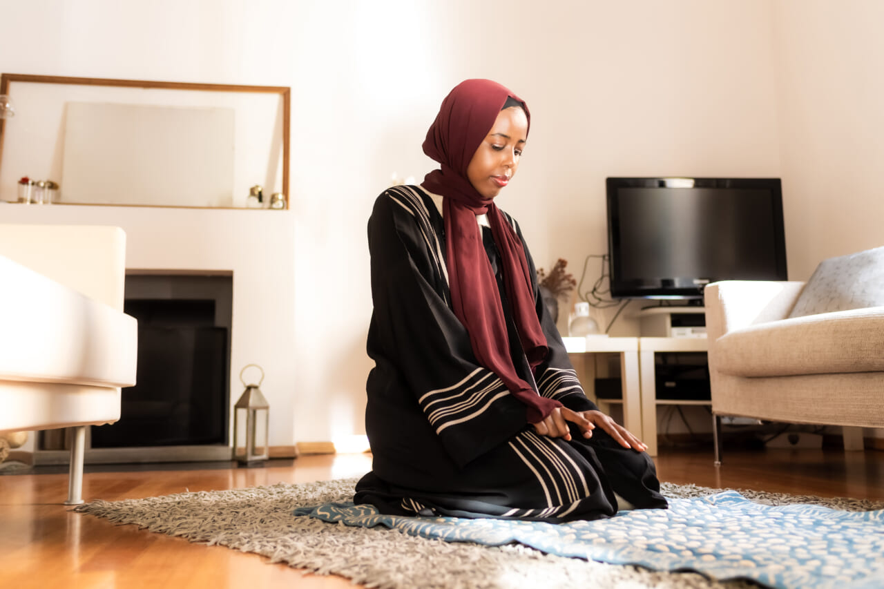 A Muslim woman kneels to pray