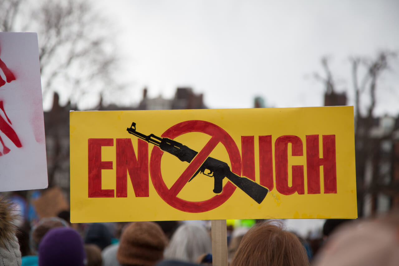 Sign reading "Enough" with an image of a gun