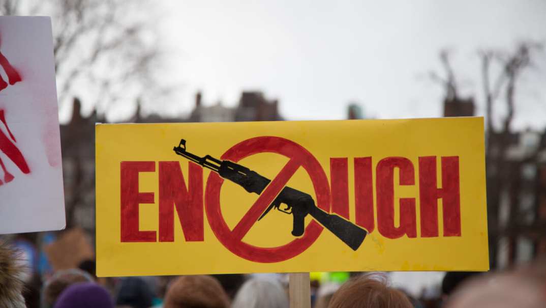 Sign reading "Enough" with an image of a gun