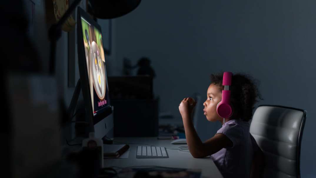 A child wearing headphones looks at a computer screen
