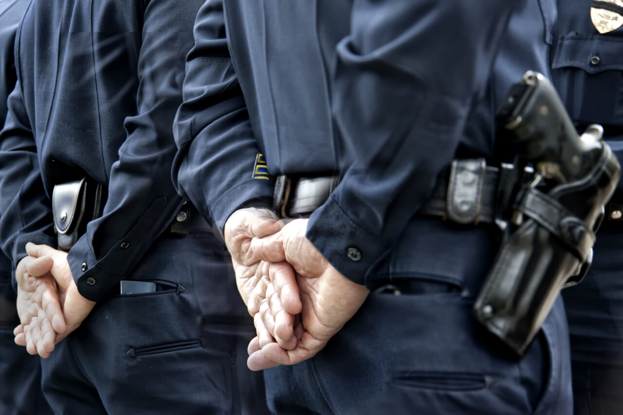 Police officers with their hands behind their backs