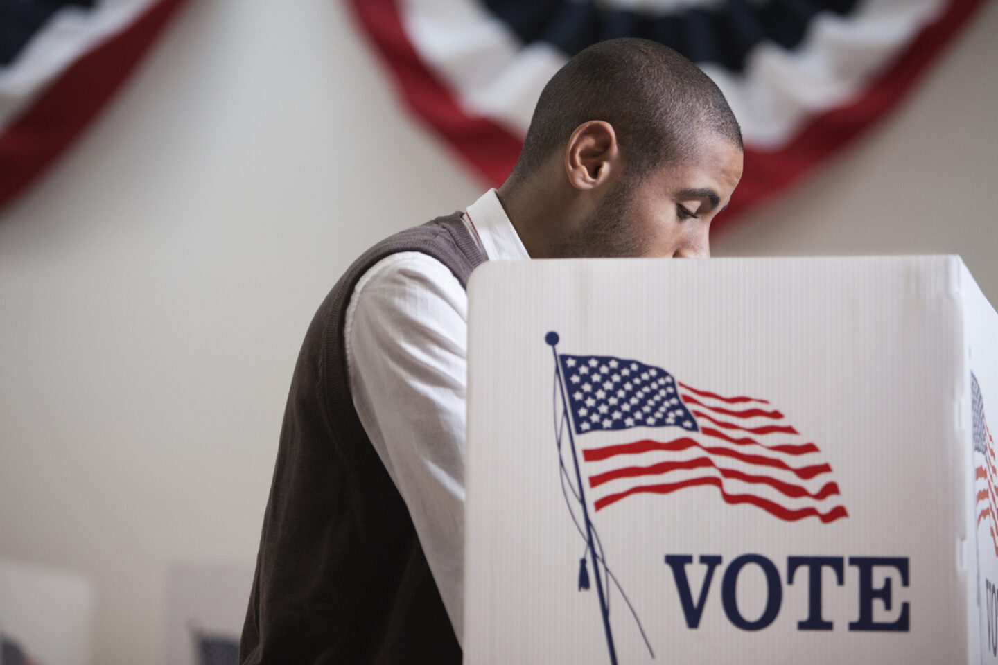 Hispanic voter voting in polling place A Black male voter inside a voting booth