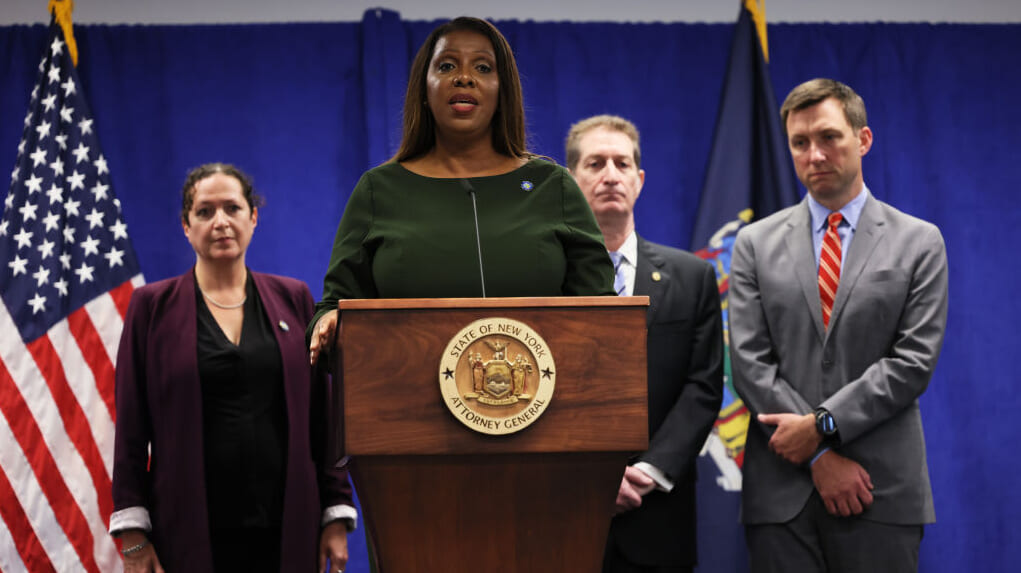 New York Attorney General Letitia James stands at a podium wearing dark green