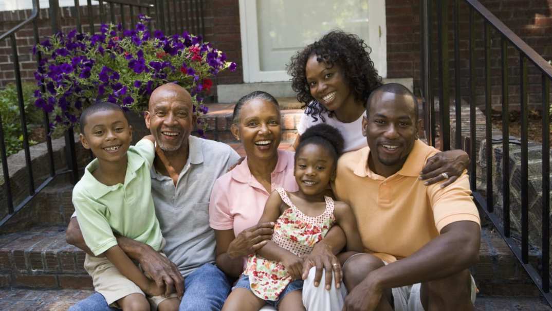 A family sits on the steps of a house