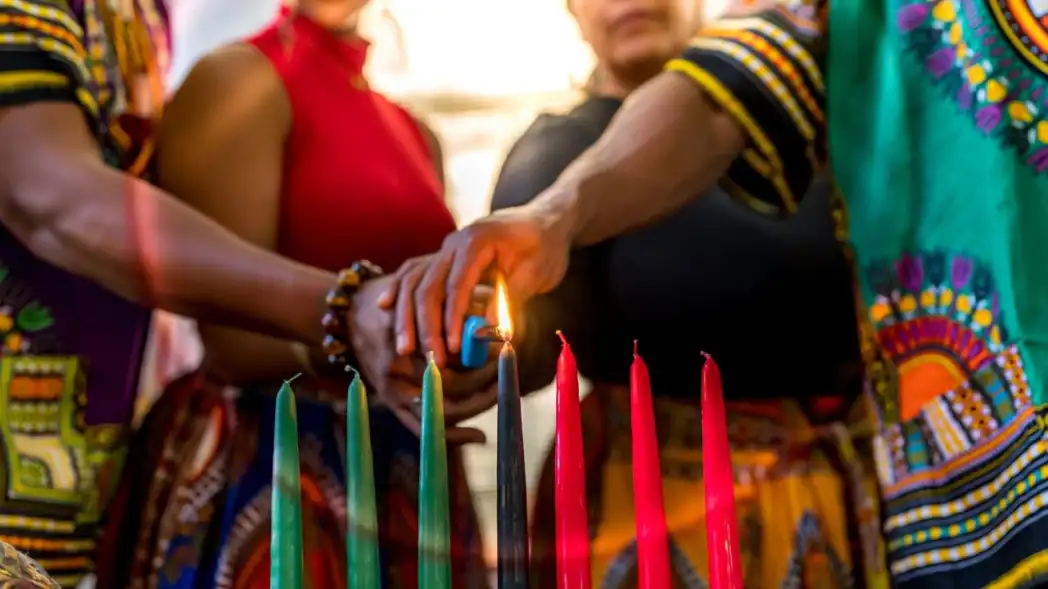 A family lighting the black Kwanzaa candle