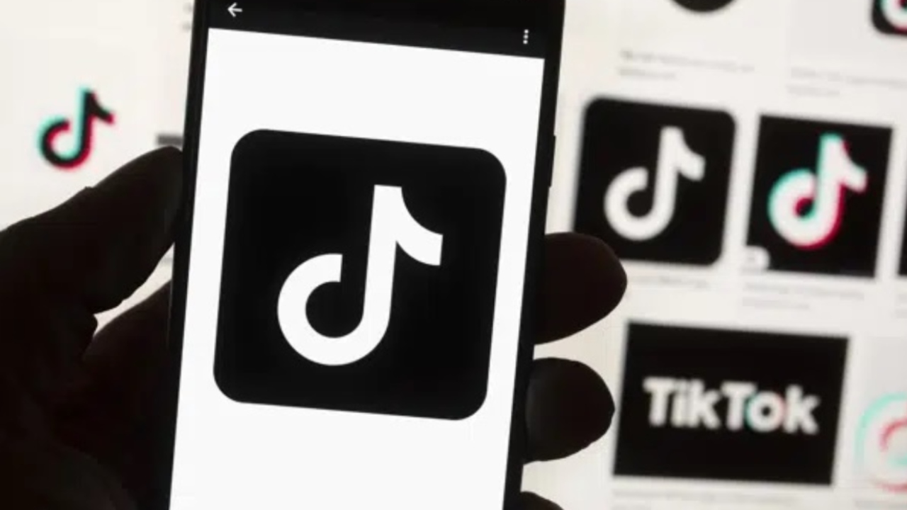 The TikTok logo is shown on a cell phone