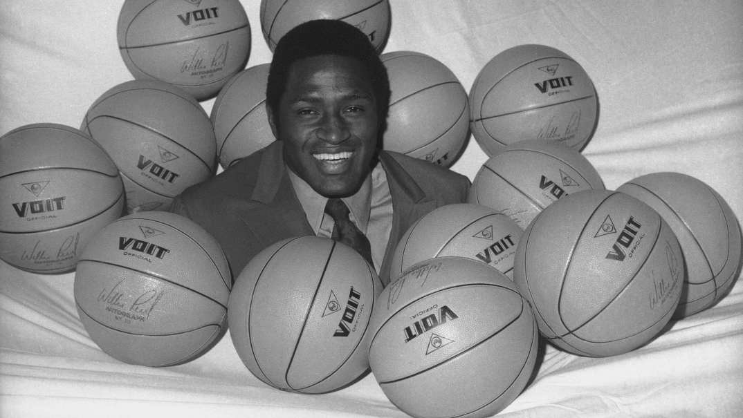 Black-and-white photo of New York Knicks NBA player Willis Reed surrounded by basketballs