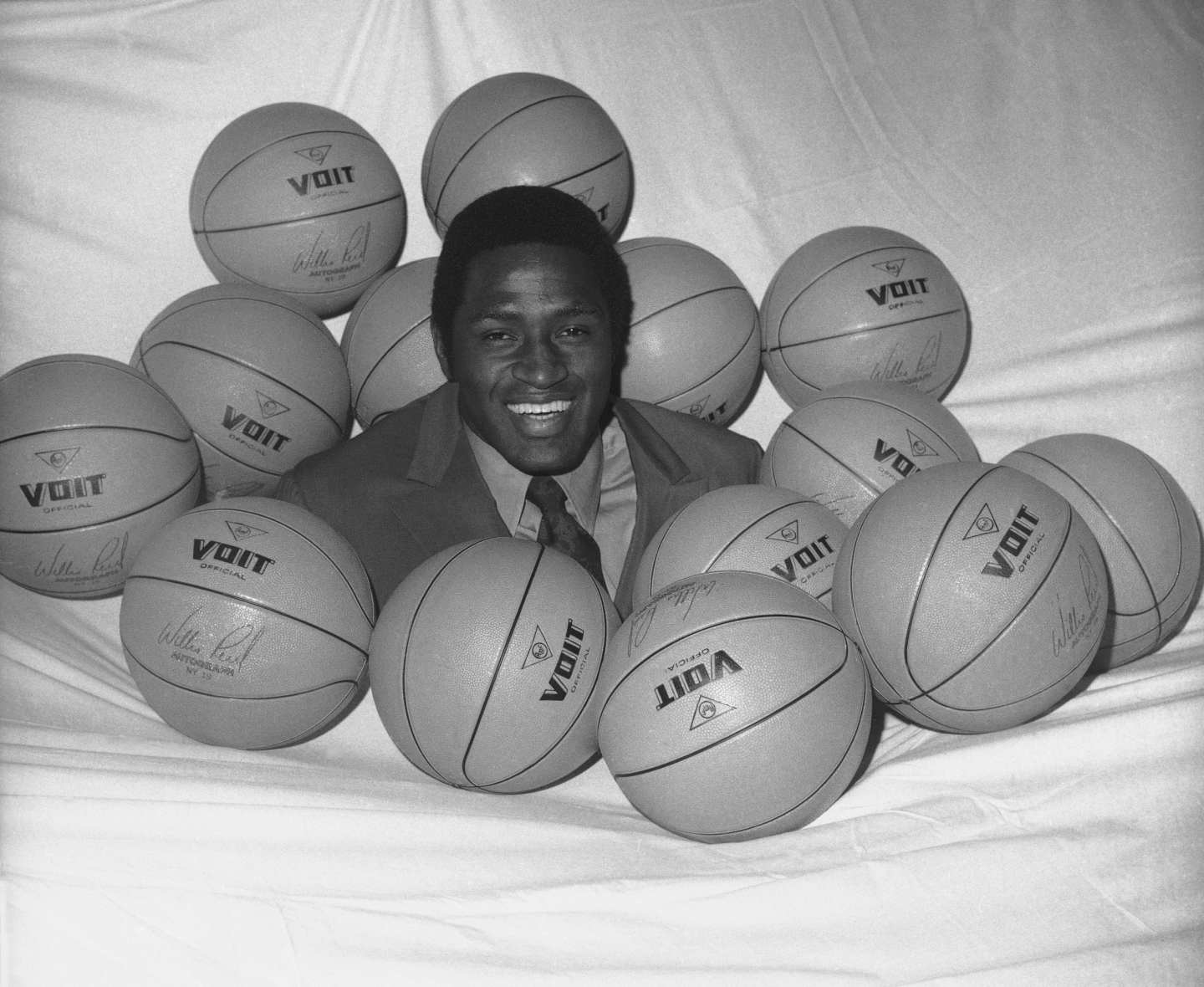 Black-and-white photo of New York Knicks NBA player Willis Reed surrounded by basketballs