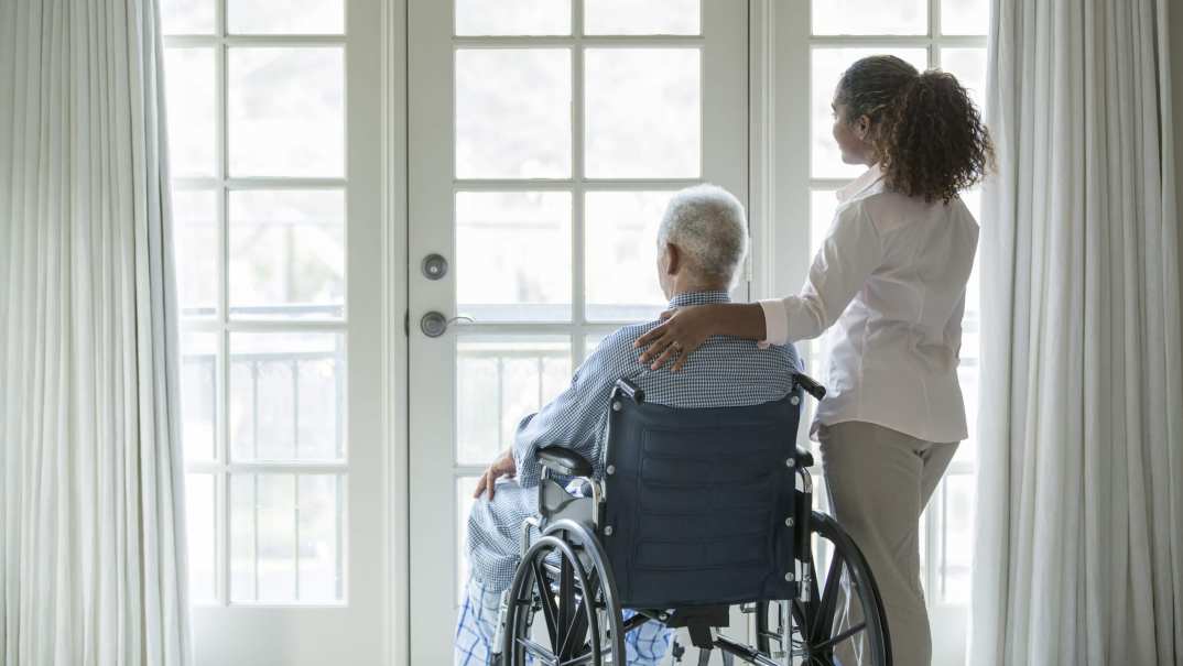 A woman stands beside a man in a wheelchair