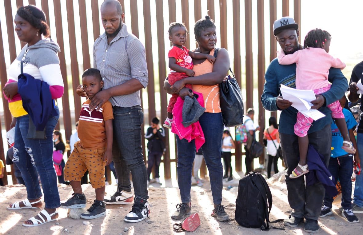 Haitian immigrants with children wait in line