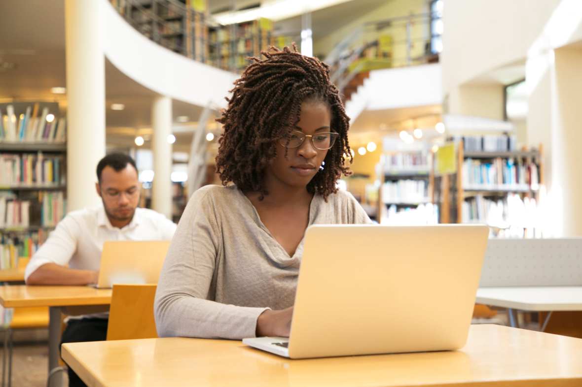 A woman uses a laptop in a library