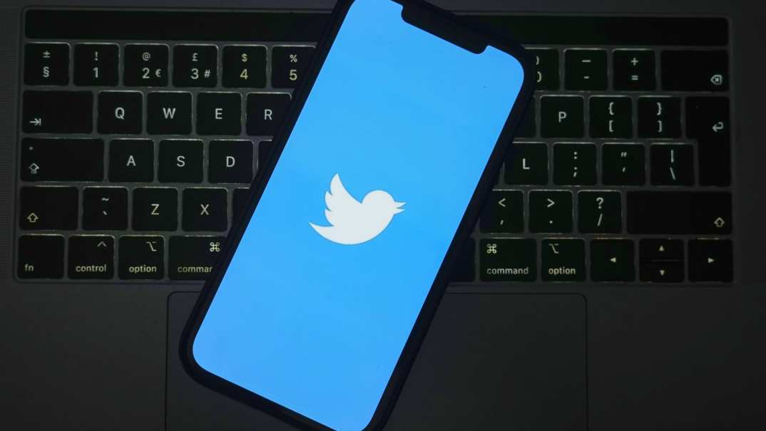 The Twitter logo on a cell phone screen over a keyboard