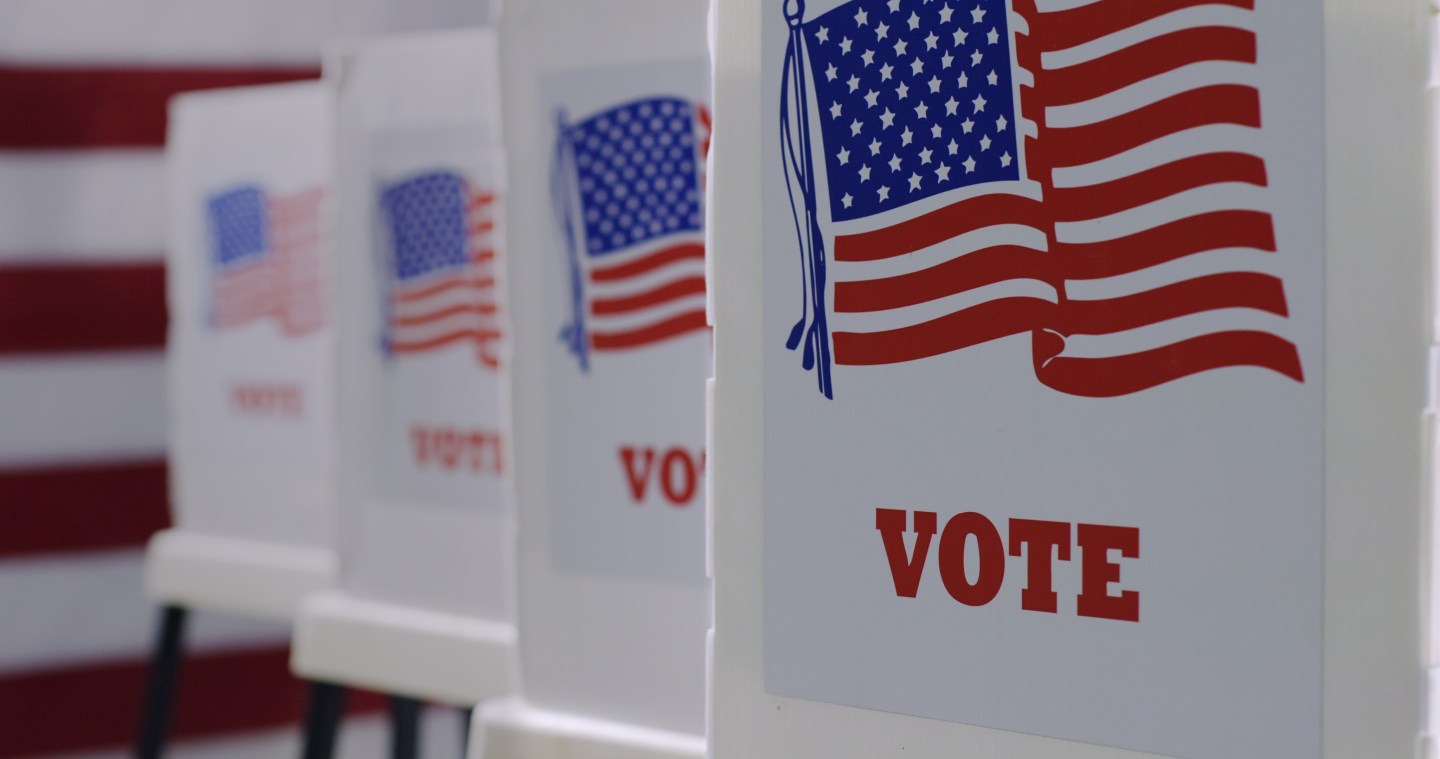 A row of voting machines with American flags and the word "Vote" on them