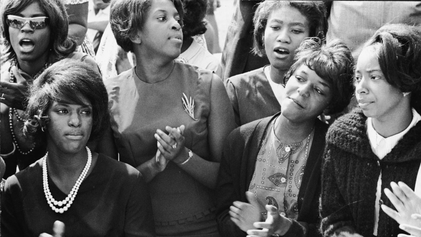 Young women clap and sing along to a freedom song