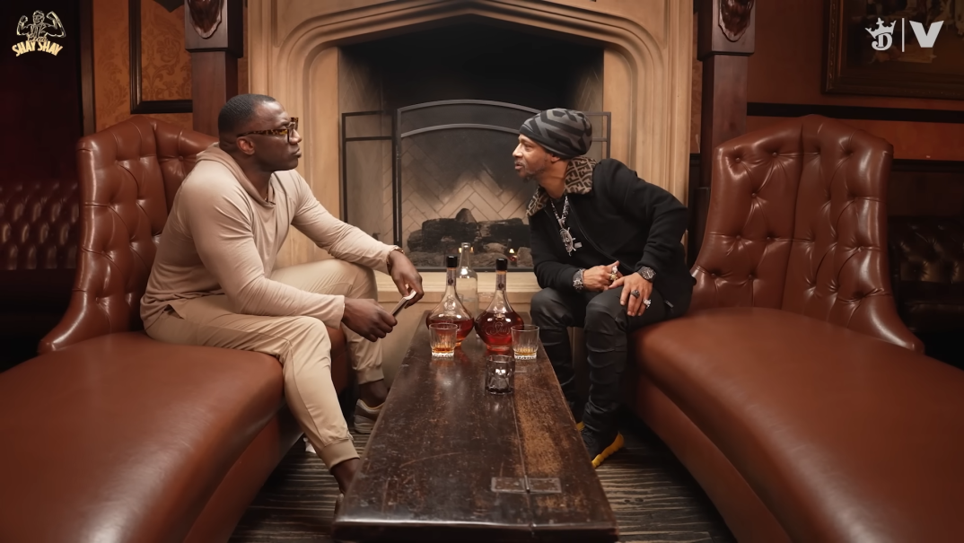 NFL Hall of Famer Shannon Sharpe and comedian Katt Williams sit on either side of a wooden table