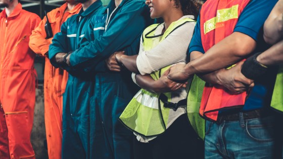 A group of workers with arms crossed holding hands