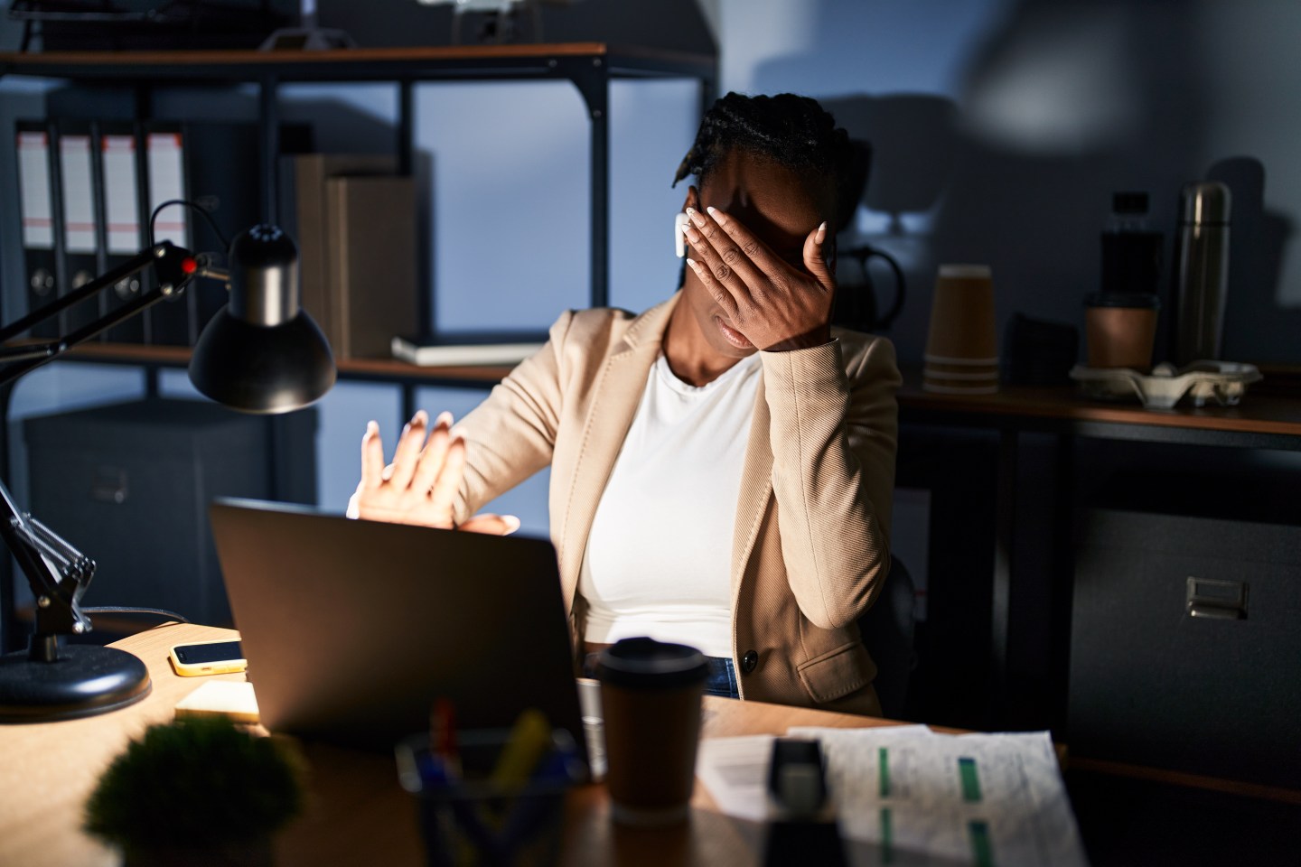 A woman covers her eyes at an image on her laptop