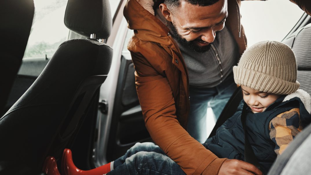 A man buckles a child into a carseat