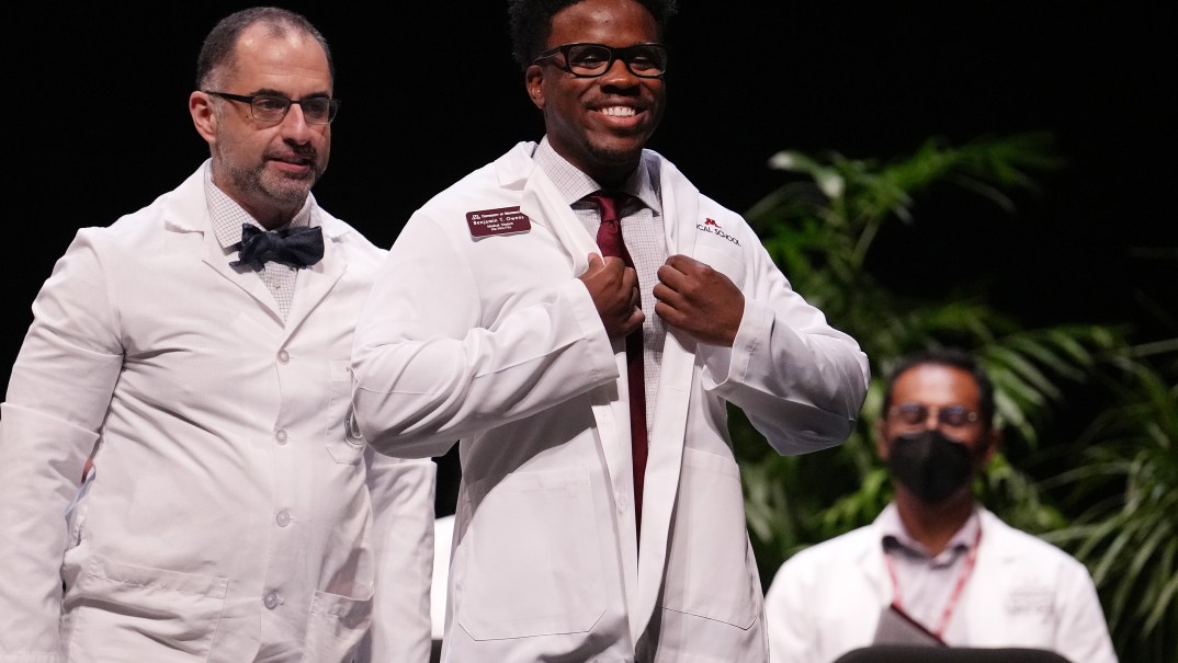 Medical student Benjamin Owens smiles as he gets his white coat from Dr. Nersi Nikakhtar