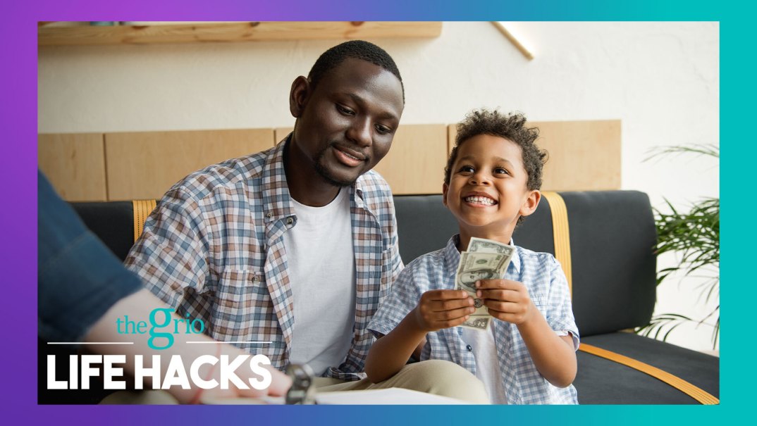 A man sits by a young boy holding $100 bills and smiling