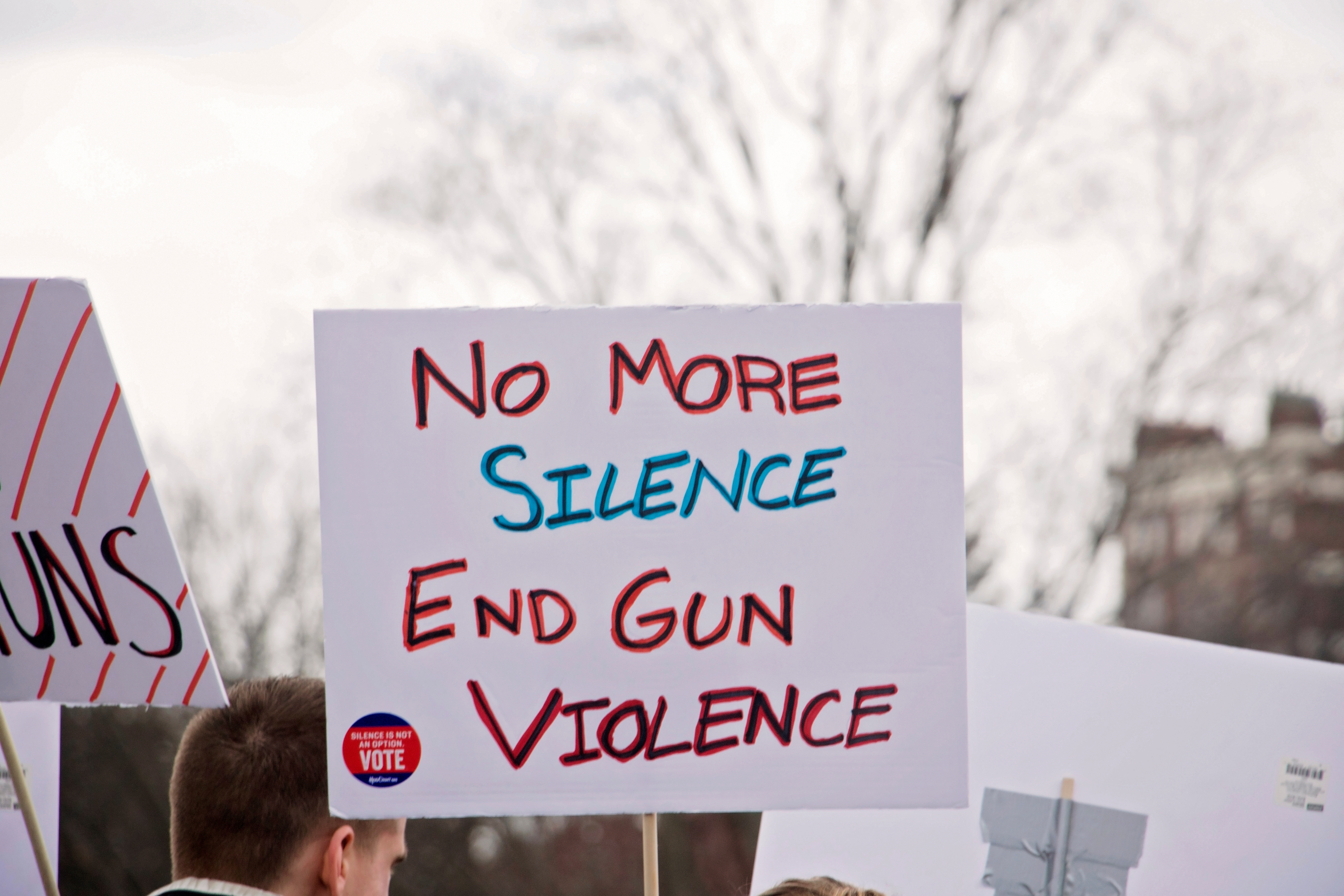 A protest sign reads "No more silence, End gun violence"