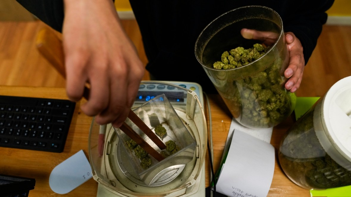 Budtender Rey Cruz weighs cannabis for a customer