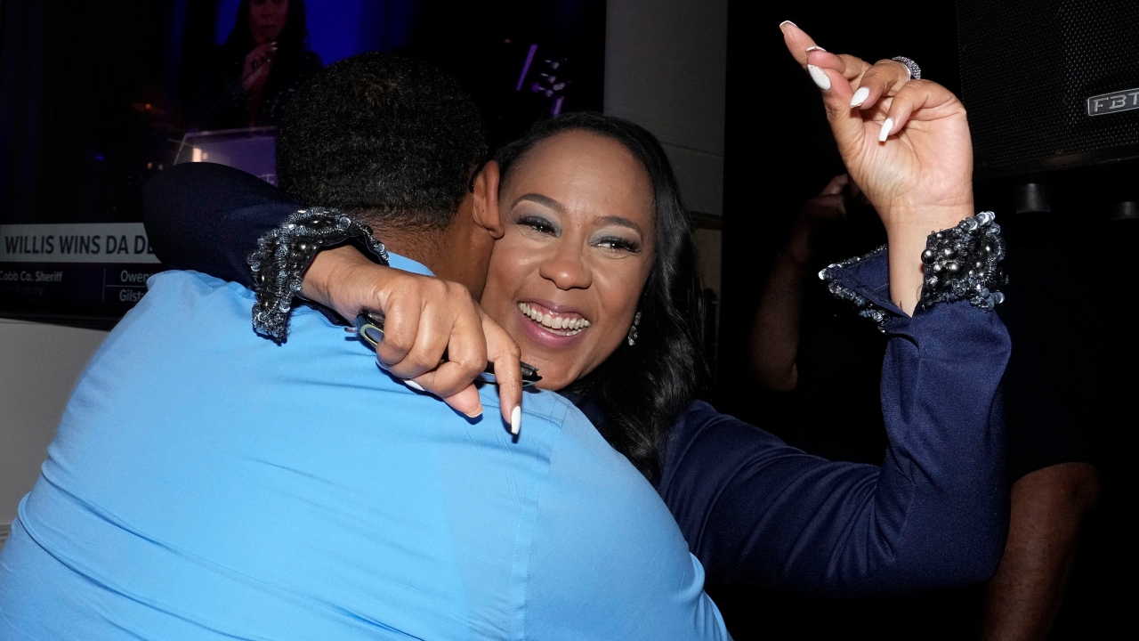 Fulton County District Attorney Fani Willis hugs a man in a blue shirt