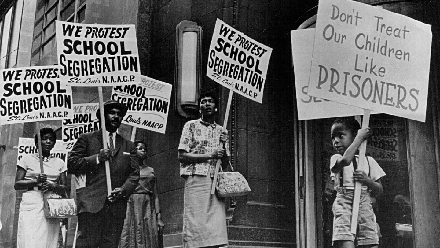 Demonstrators picket in front of a school board office protesting segregation